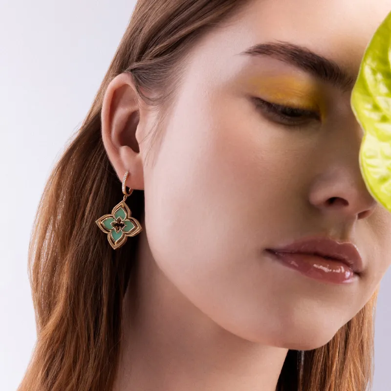 Model wearing floral earrings with turquoise accents, showcasing fine jewelry.