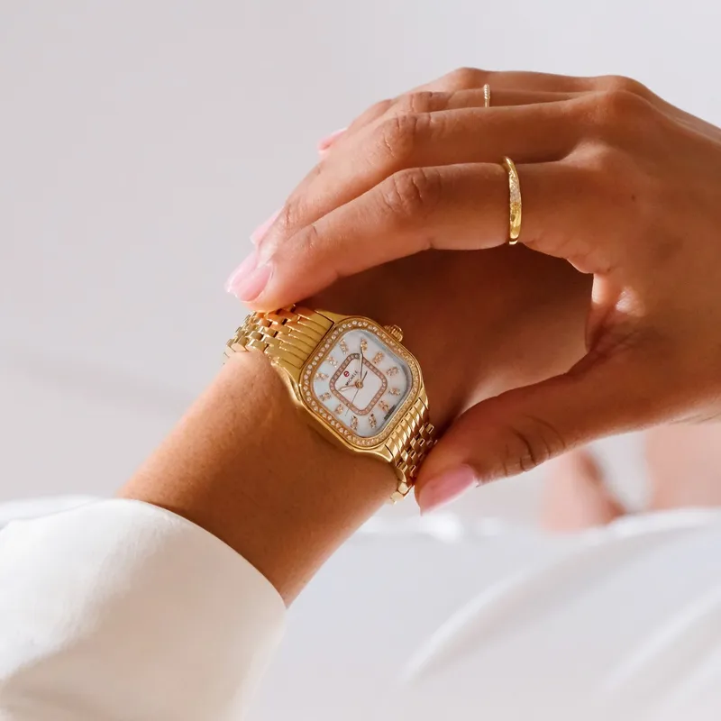 Gold watch with a diamond-studded face worn on a wrist, showcasing elegance and style.