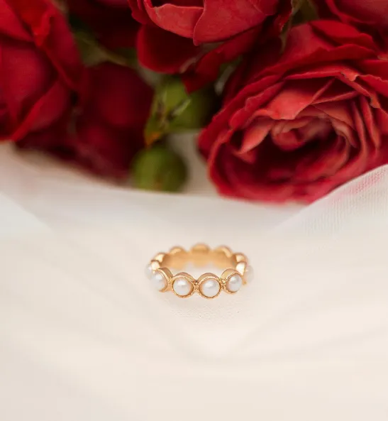 Gold ring with pearls surrounded by red roses, symbolizing love and elegance. Visit P.J. Rossi Jewelers for more.