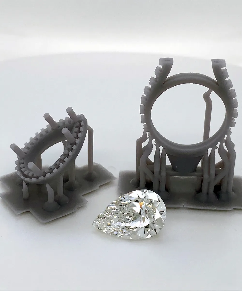 3D-printed ring molds with a pear-shaped diamond on display.