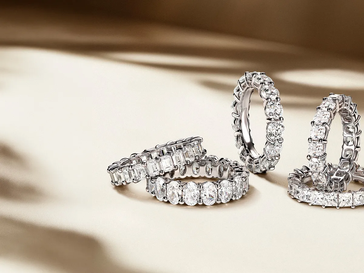 Diamond eternity rings displayed on a soft, beige background.