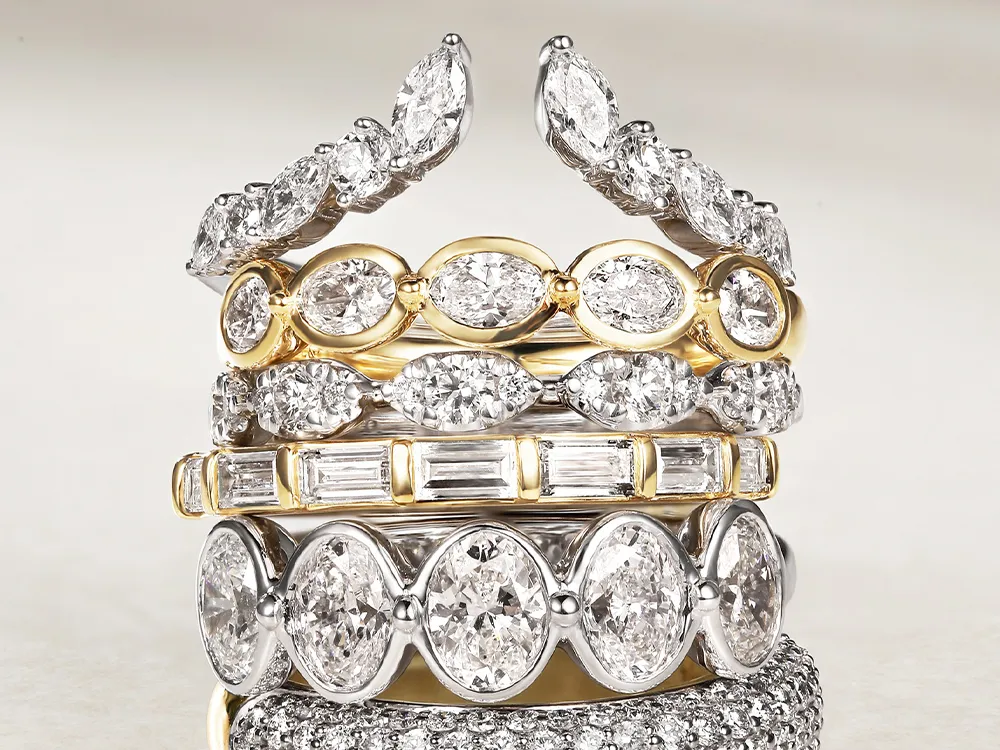 Stack of gold and silver diamond rings with various cuts and settings.