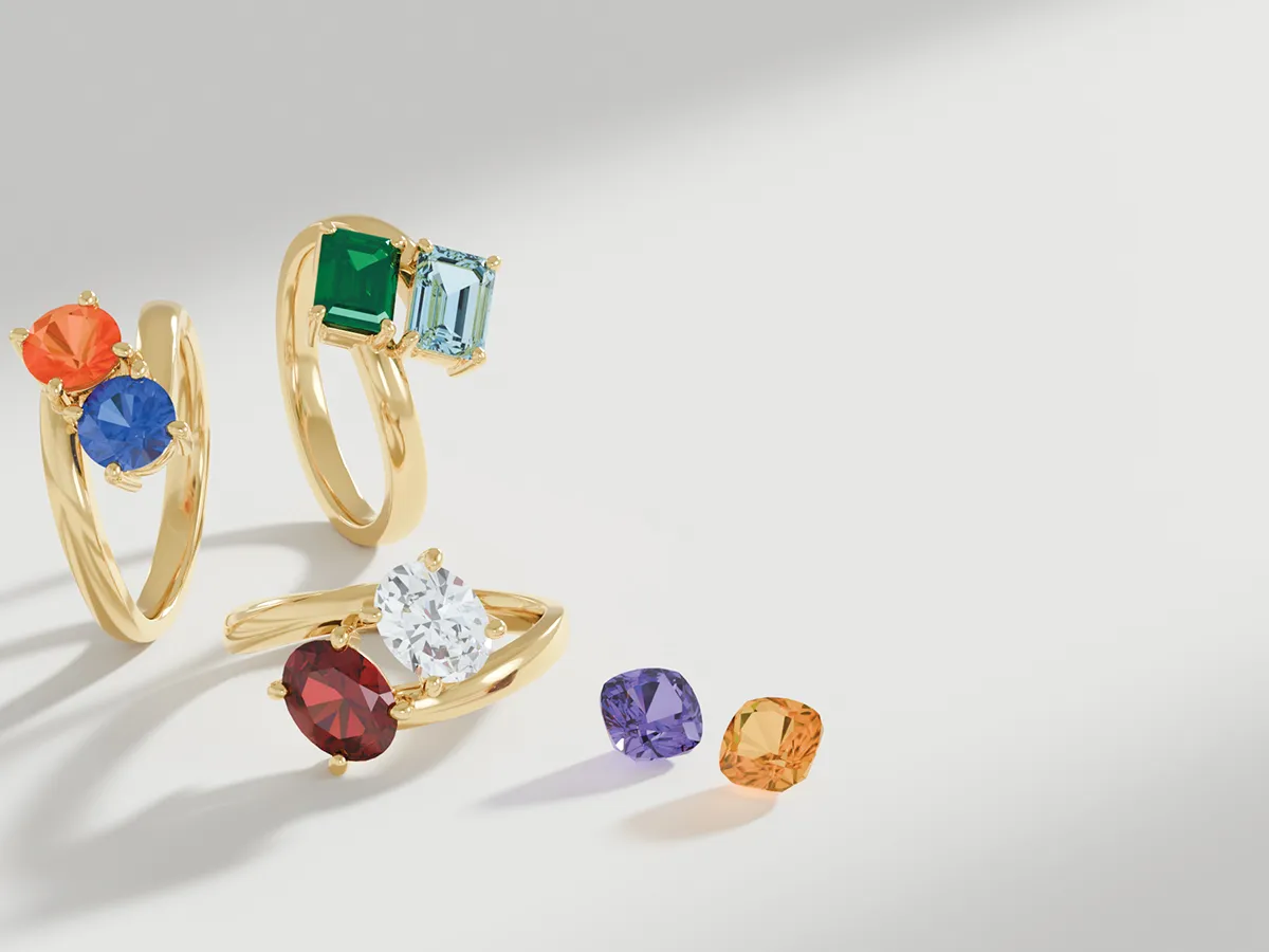 Gold rings with colorful gemstones on a light background.