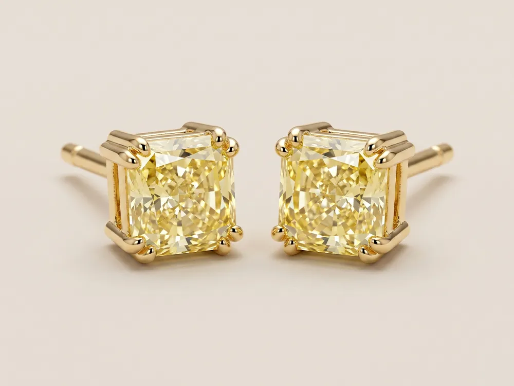 Square yellow diamond stud earrings in gold prong settings on a neutral background.
