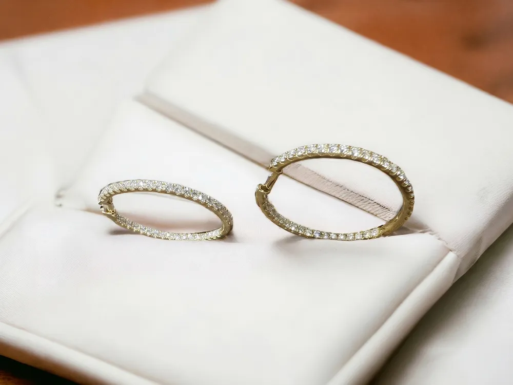 Gold hoop earrings with diamonds displayed on a white fabric background.