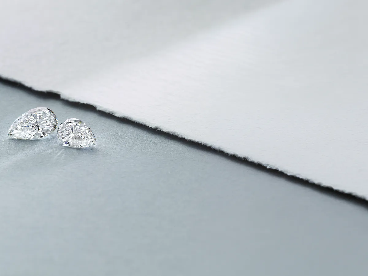 Two pear-shaped diamonds on a textured gray and white background.