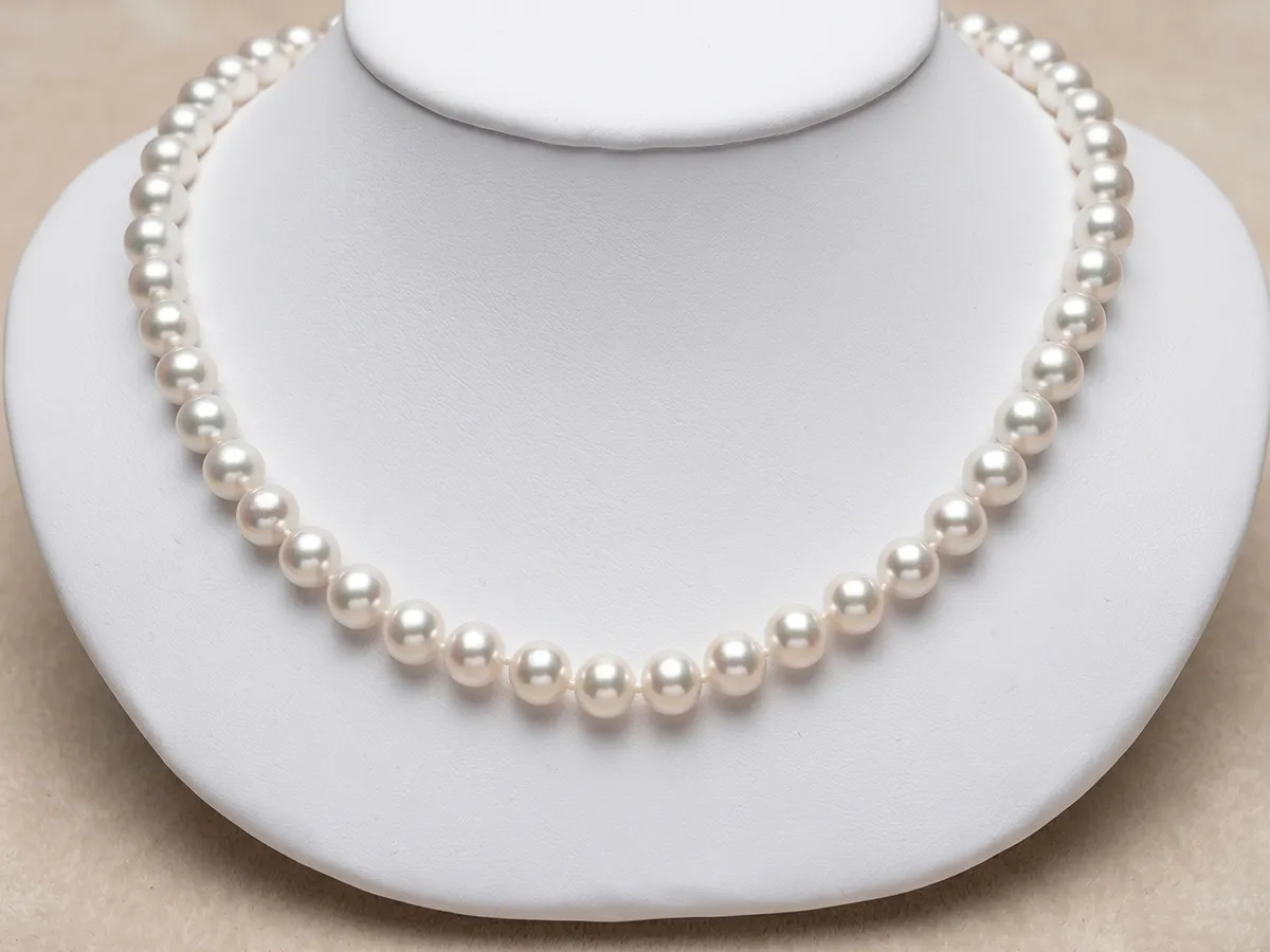 A strand of white pearls displayed on a white jewelry bust.