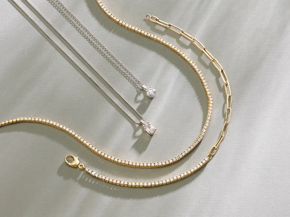 Gold and silver chains and earrings displayed on a light surface.