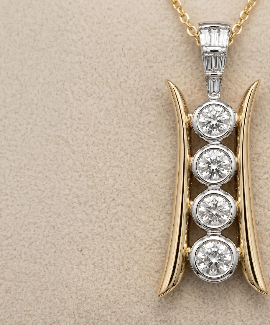 Gold pendant with four round diamonds in a vertical row on a beige background.