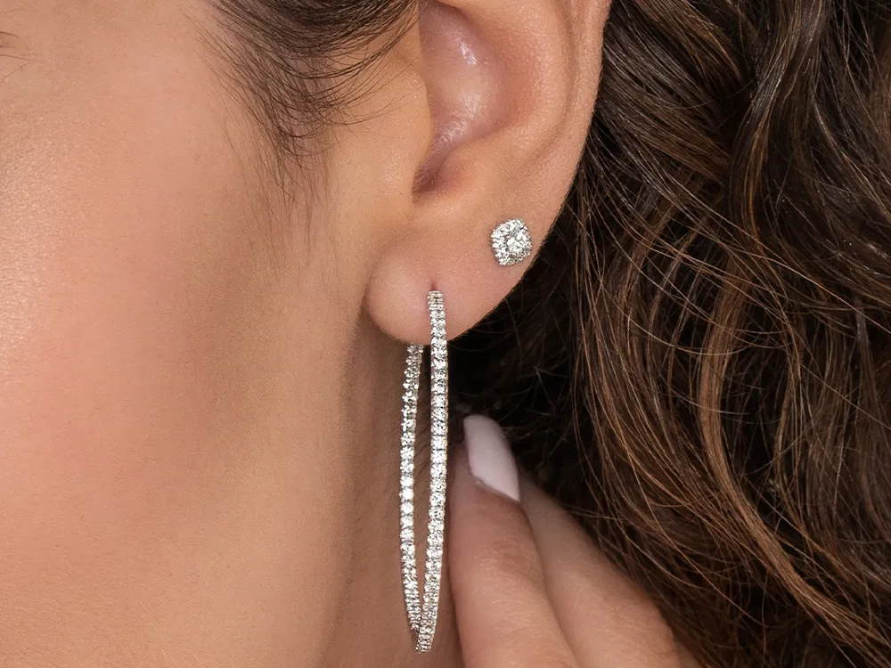 Close-up of an ear wearing diamond hoop and stud earrings.