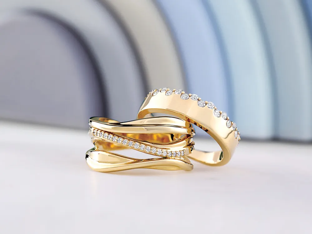 Two gold rings with diamond accents on a white surface, with a blurred background.