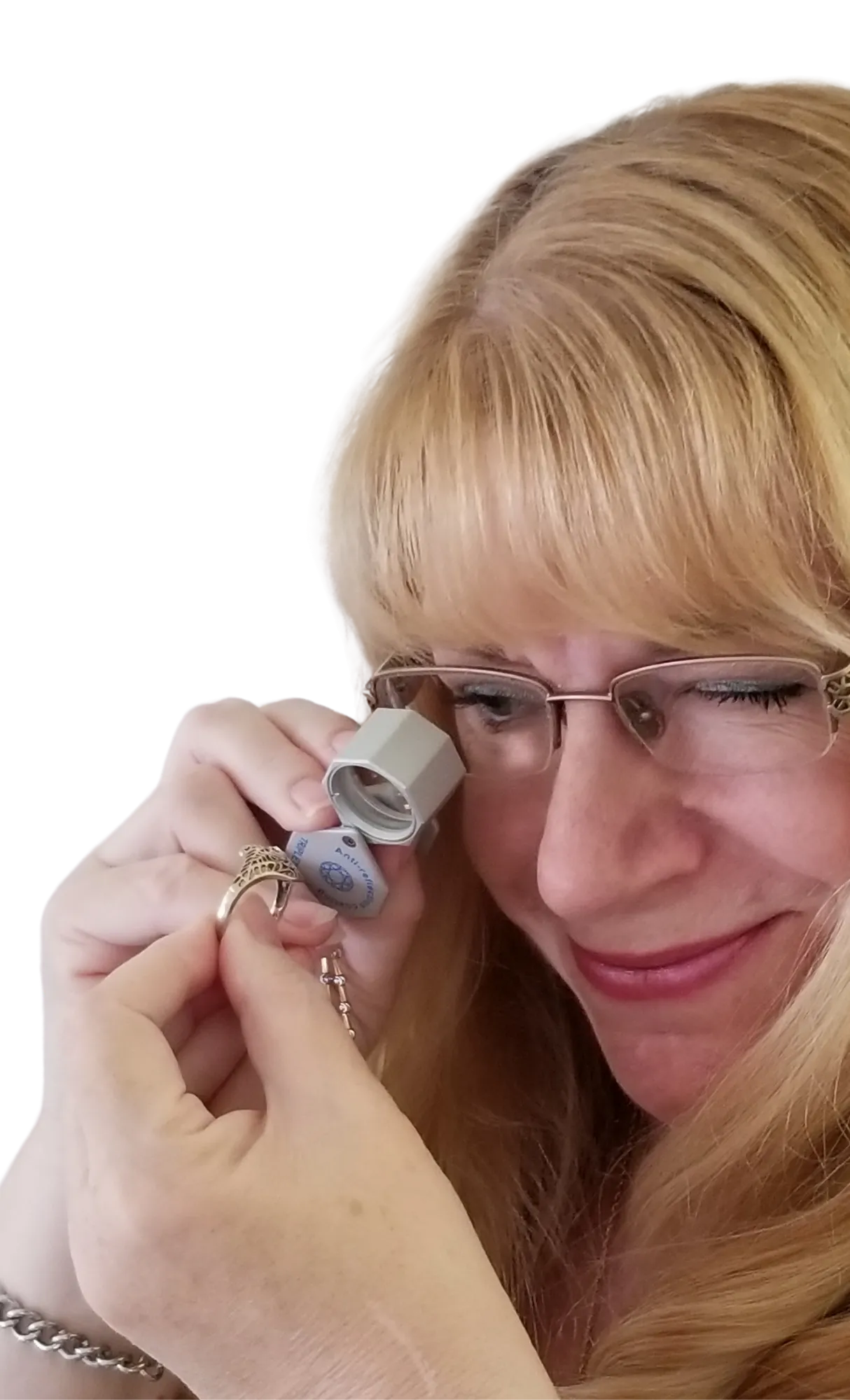 Woman examining a ring with a loupe, smiling, showcasing her interest in jewelry at Masterpiece Jewelers in Daytona Beach.