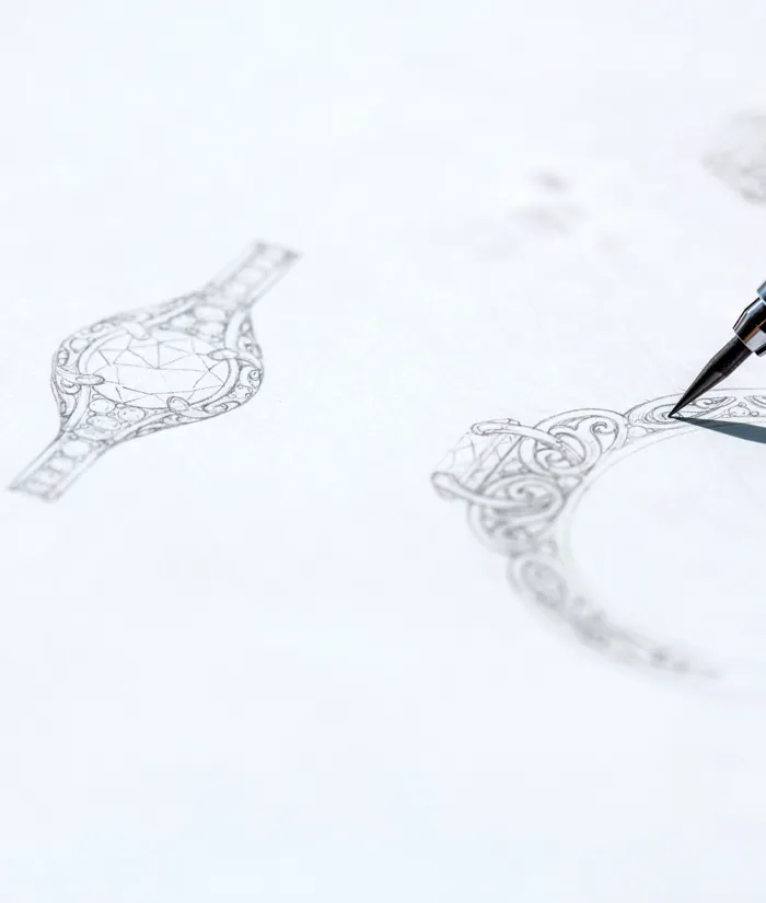 Detailed sketches of intricate jewelry designs with a pen in focus, showcasing artistry in jewelry creation.