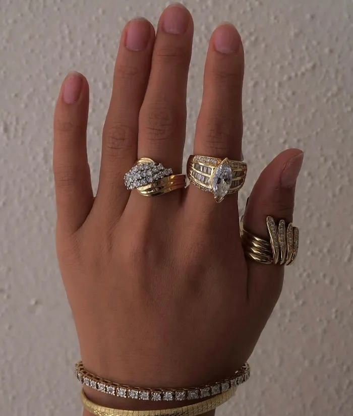 A hand adorned with multiple gold and diamond rings, showcasing elegant jewelry from Masterpiece Jewelers in Daytona Beach.