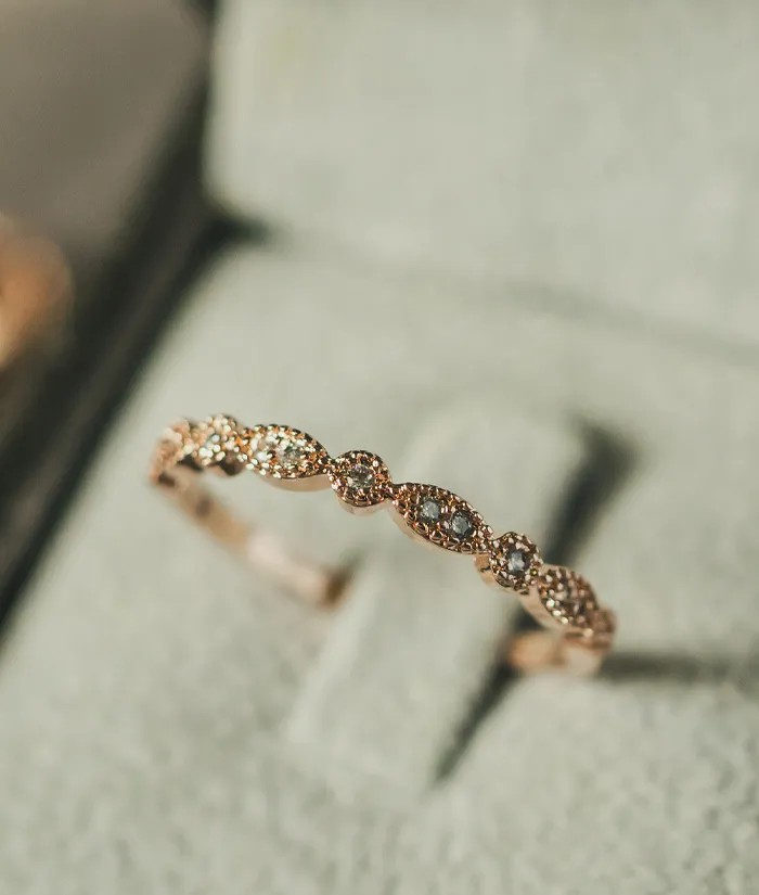 Elegant rose gold ring with sparkling diamonds, displayed on a soft gray background at Masterpiece Jewelers in Daytona Beach.