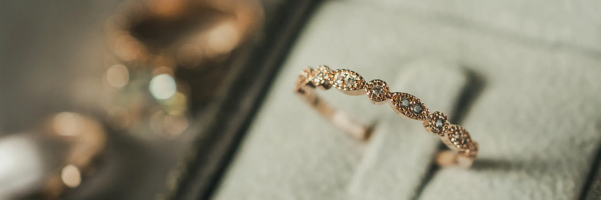 Elegant rose gold ring with sparkling diamonds, displayed on a soft gray background at Masterpiece Jewelers in Daytona Beach.