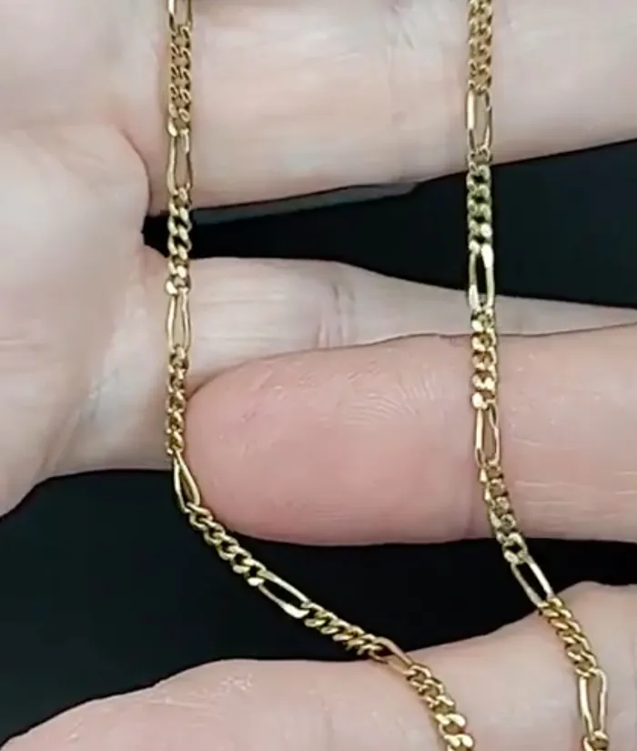 Close-up of a gold chain held in a hand, showcasing its intricate links. Visit Masterpiece Jewelers for fine jewelry.
