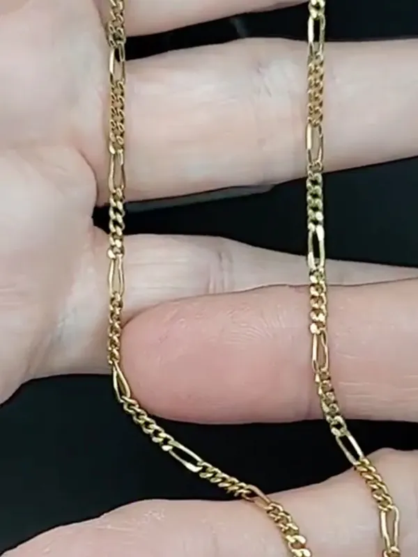 Gold chain held in a hand, showcasing its intricate design. Explore more chains at Masterpiece Jewelers.