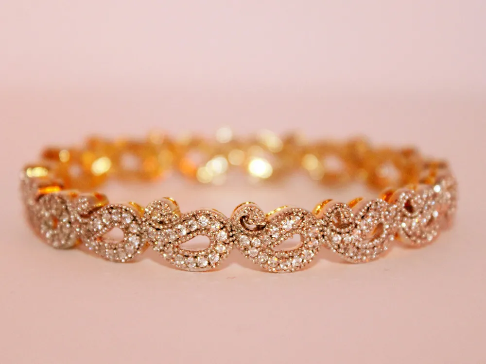 Elegant gold bracelet adorned with sparkling diamonds, showcasing intricate design. Visit Masterpiece Jewelers for more!