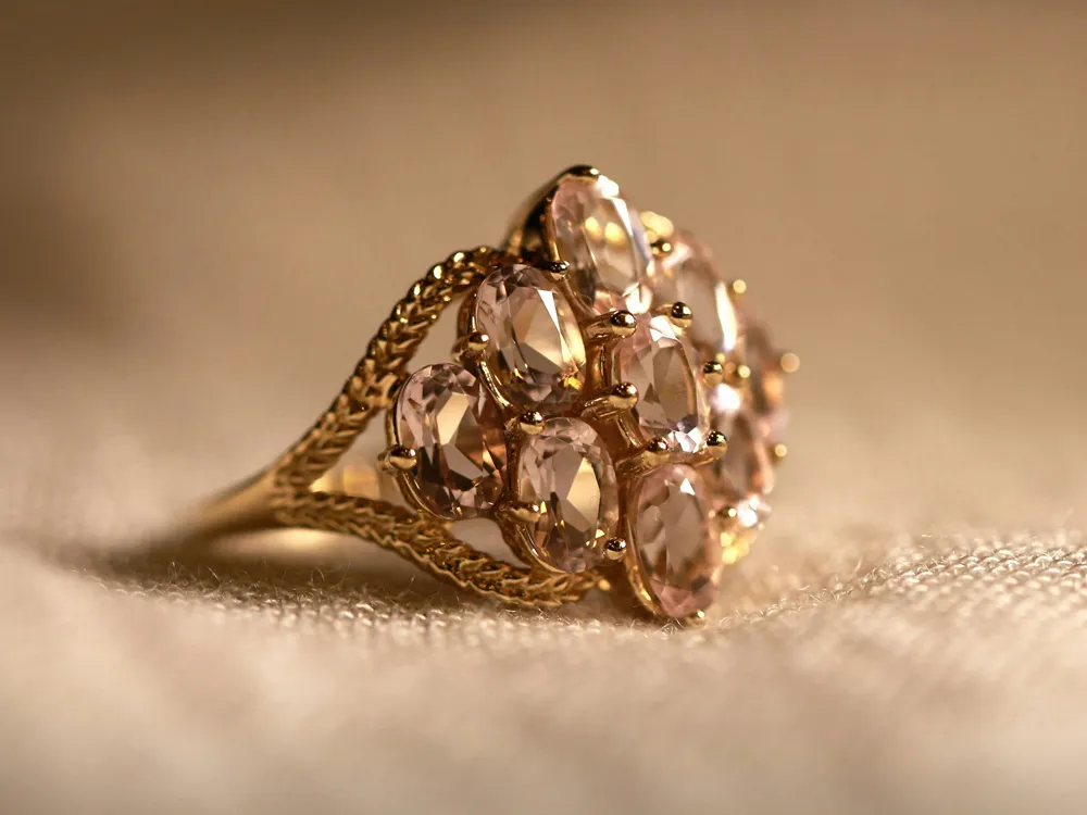 Gold ring with multiple pink gemstones, showcasing intricate design. Visit Masterpiece Jewelers for fine jewelry.