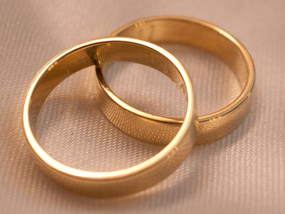 Two gold wedding rings resting on a soft surface, symbolizing love and commitment. Visit Masterpiece Jewelers for more.