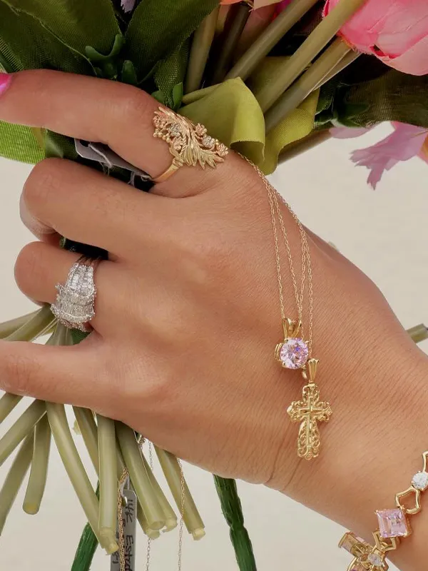 Close-up of a woman wearing gold hoop earrings, layered necklaces, and statement rings, showcasing fine jewelry.