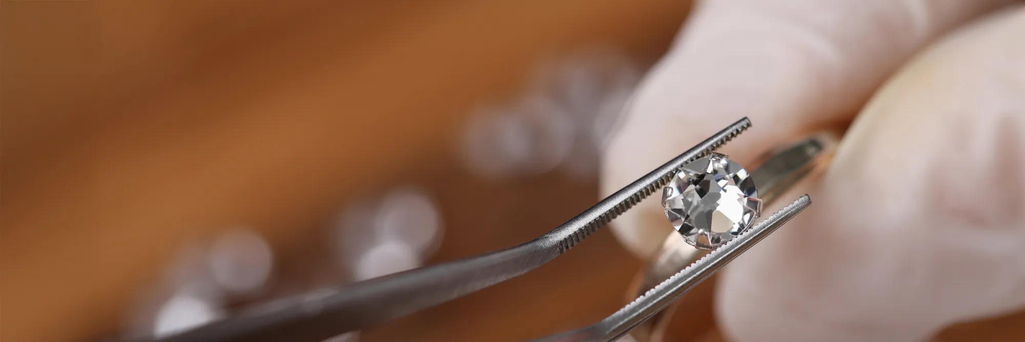 Jeweler using tweezers to hold a diamond ring for evaluation at Masterpiece Jewelers in Daytona Beach. Start a Project.