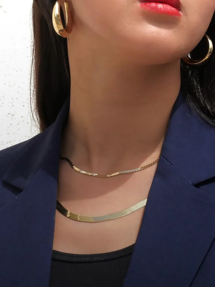 Model wearing gold earrings and layered necklaces, showcasing elegant jewelry from Masterpiece Jewelers in Daytona Beach.