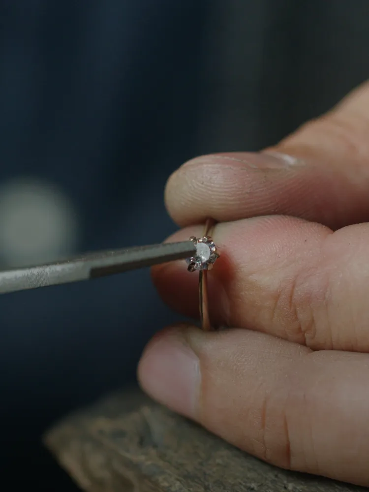 A jeweler inspects a diamond ring with precision tools, ensuring quality craftsmanship at Masterpiece Jewelers in Daytona Beach.