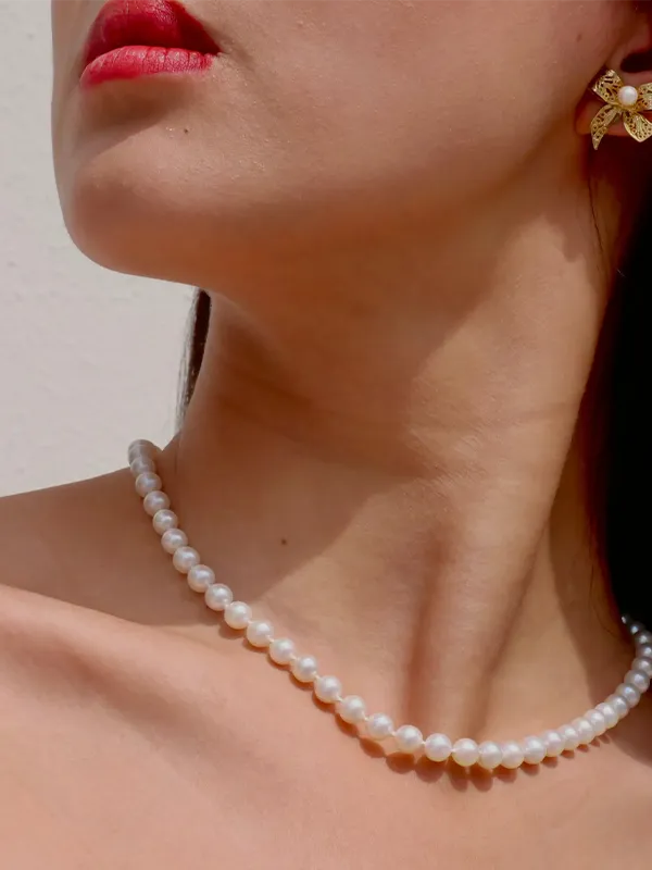 Model showcasing pearl jewelry, including earrings, rings, and bracelets, against a textured background.
