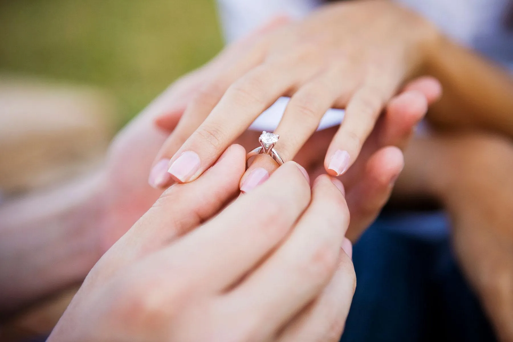 Engagement Ring being placed on ring finger with solitaire diamond. Find engagement rings at The Jewelry Source El Segundo, CA