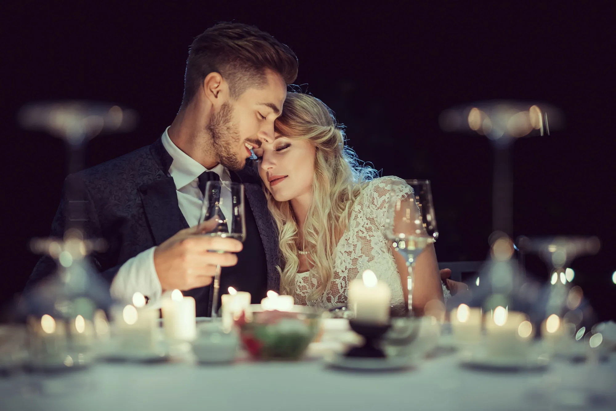 Romantic couple sharing a moment at a candlelit dinner, celebrating love and intimacy. Falls Jewelers, Concord, NC.