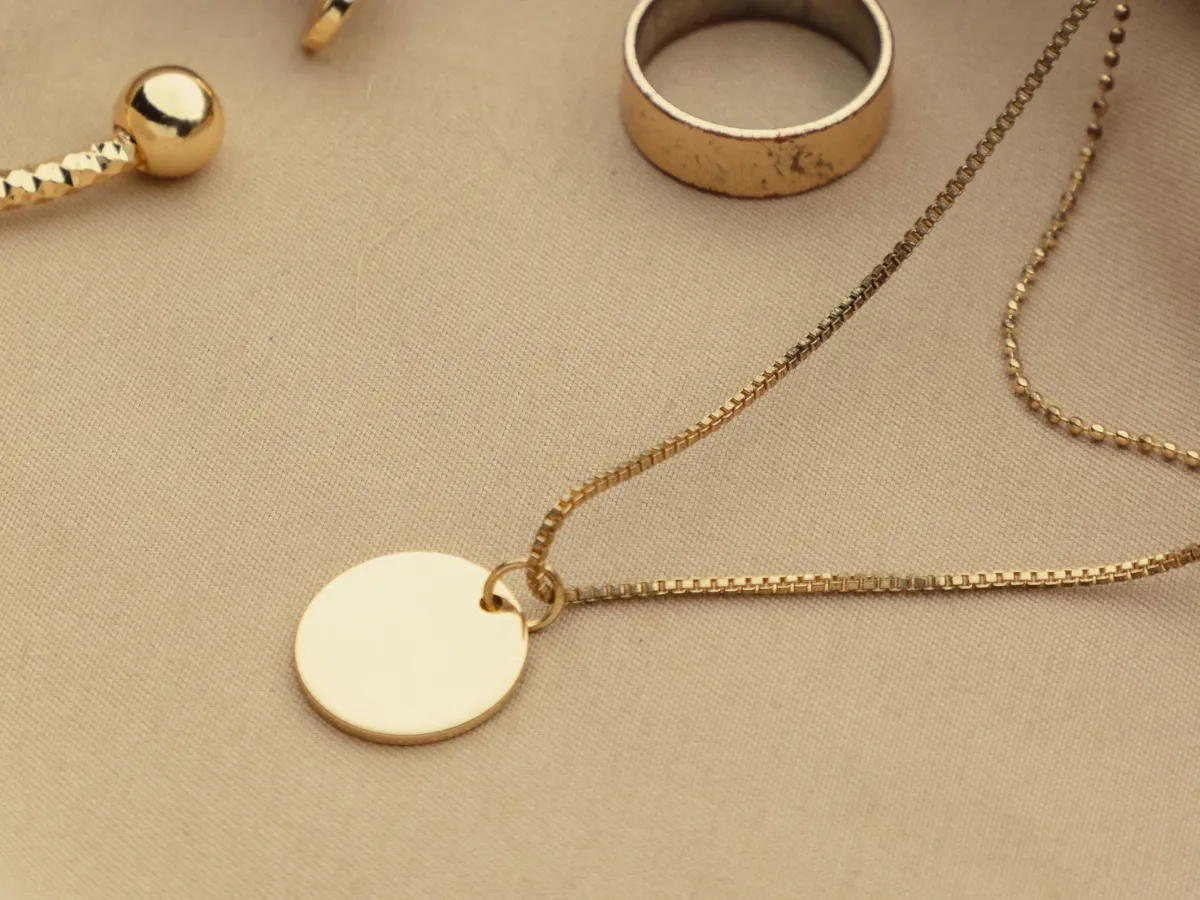 Gold necklace with a round pendant.