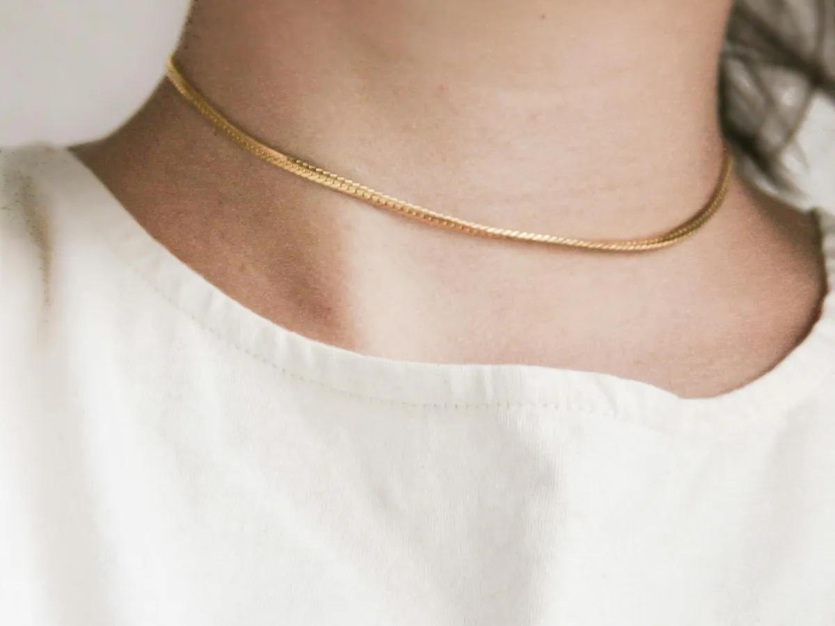 Thin gold choker on white shirt.