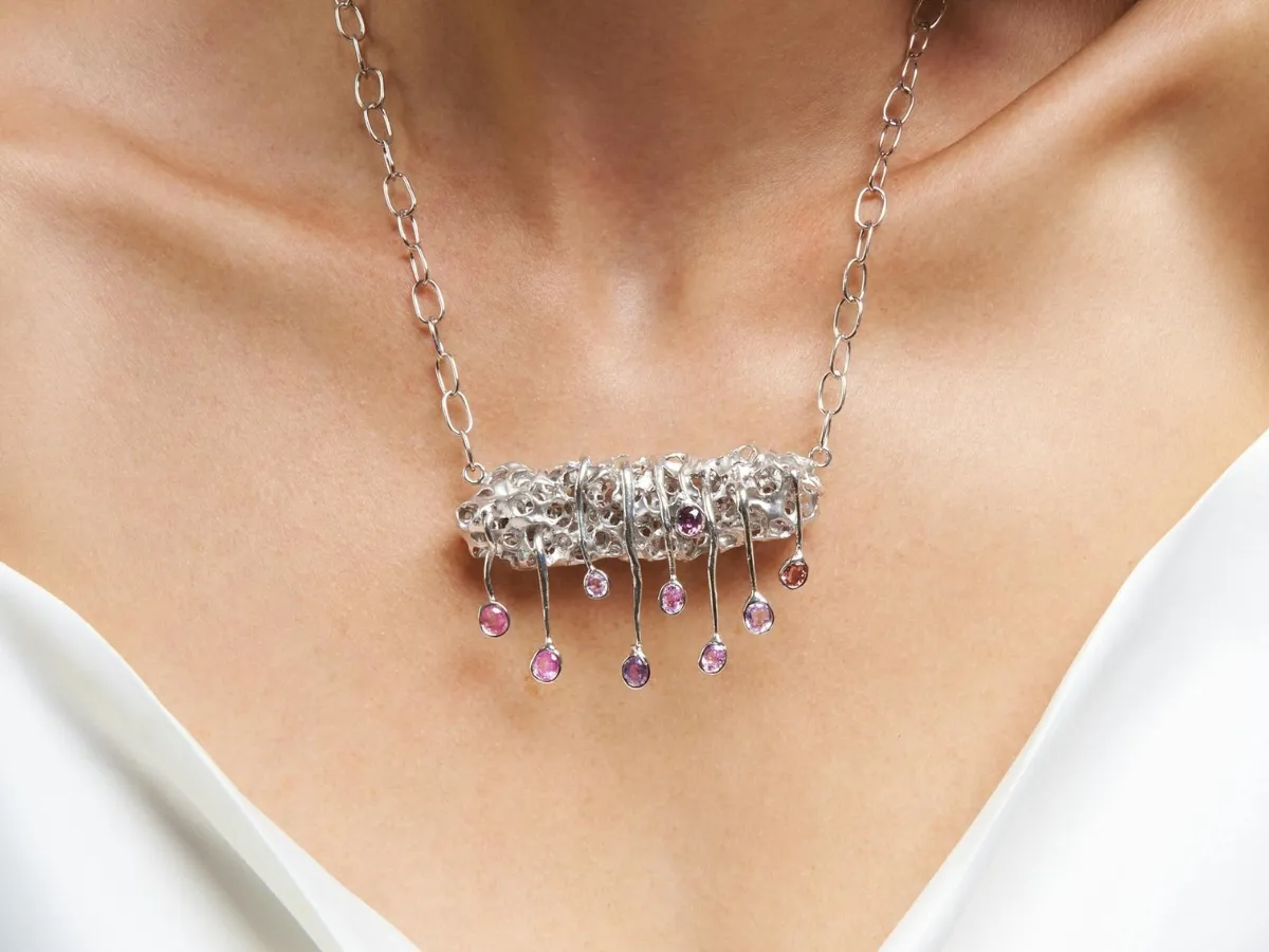 Silver necklace with gemstones hanging from a chain.