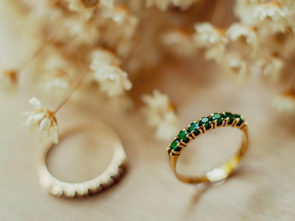 Gold ring with a row of round green gemstones.