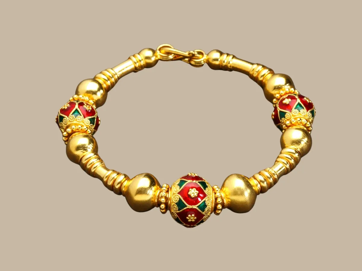 Gold-toned metal beads combined with intricately designed enamel work.