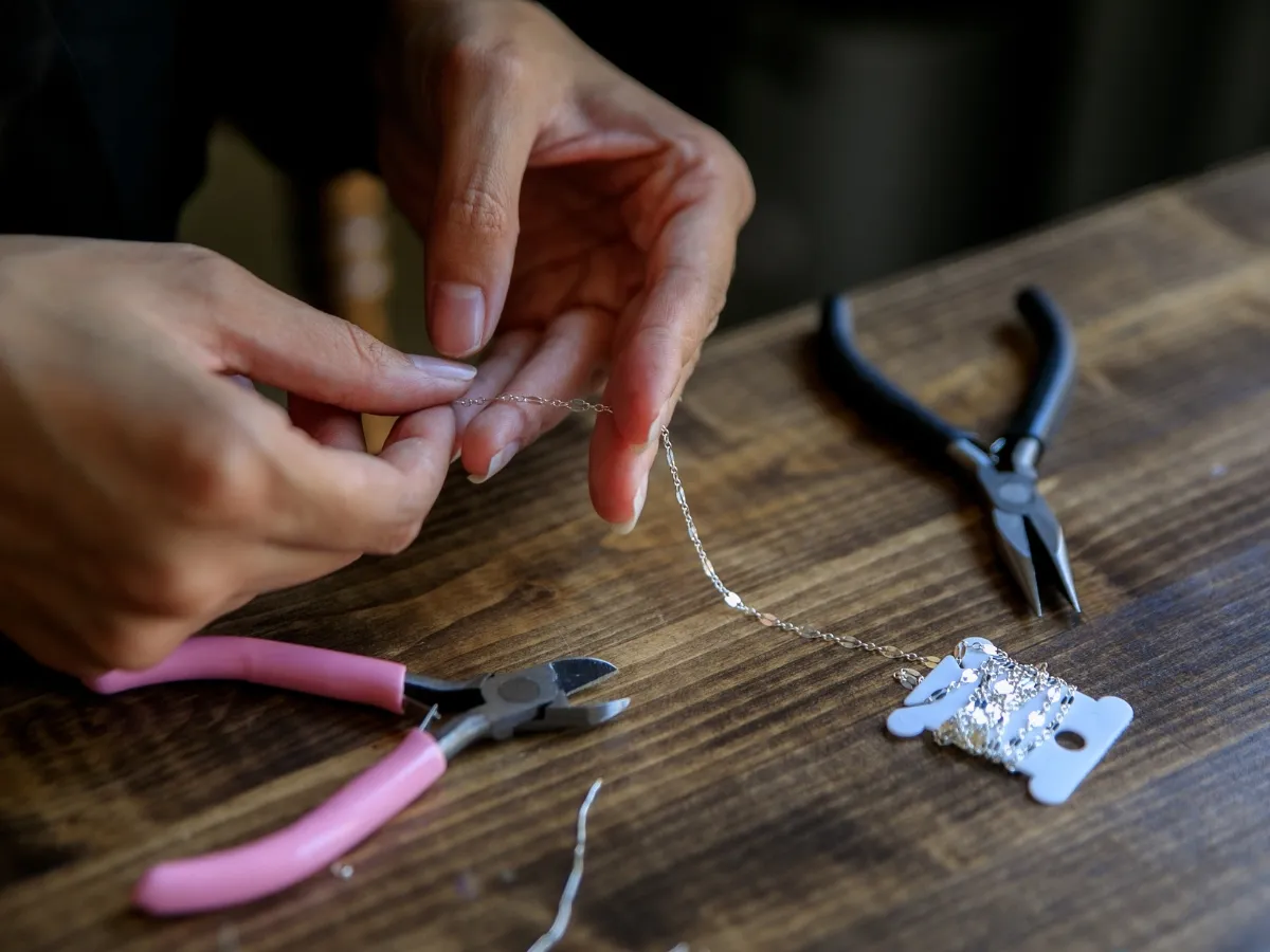 Assembling silver chain with pliers.