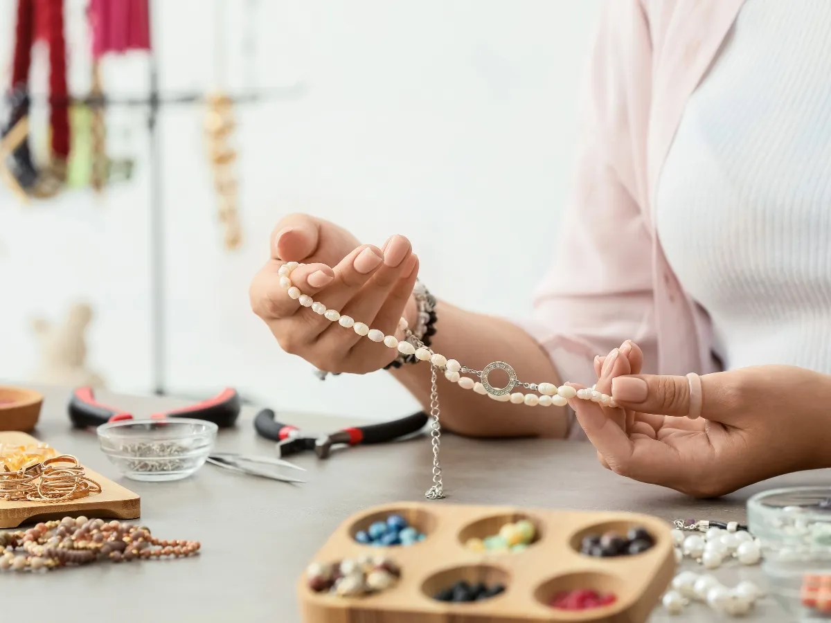Woman crafting beaded pearl necklace.