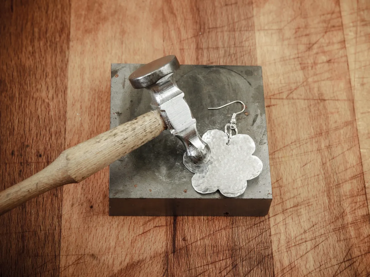 Hammered metal flower earring crafting.