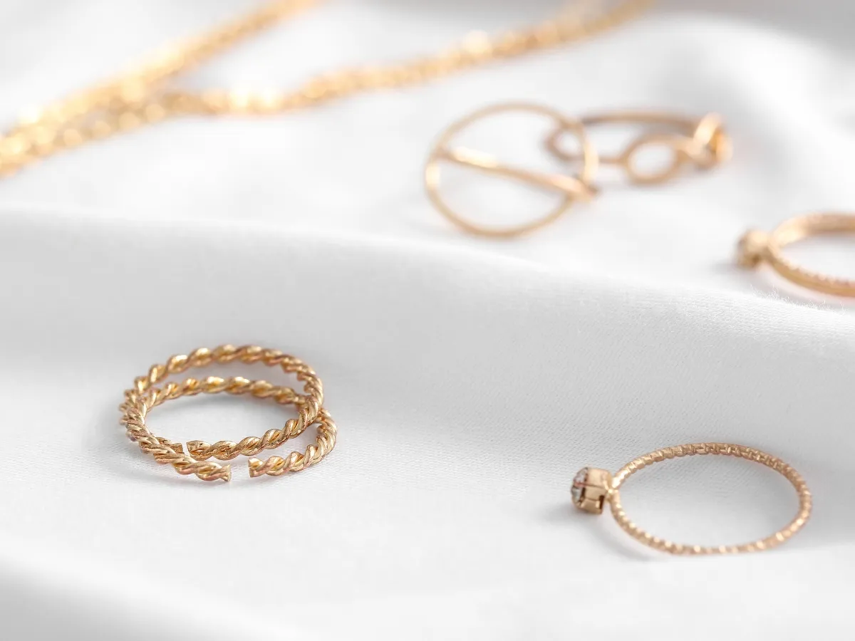 Minimalist gold rings on white cloth.