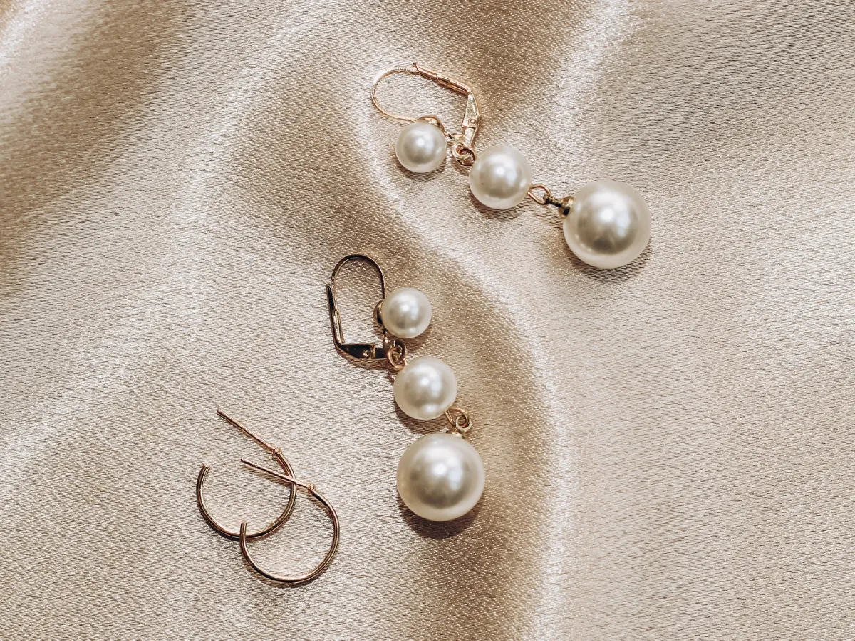 Pearl drop earrings on satin fabric.