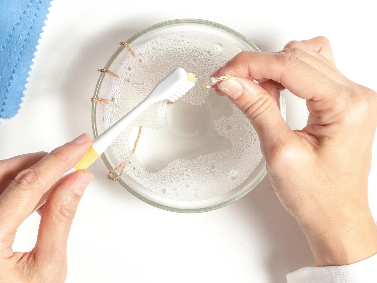 Brushing jewelry in cleaning solution.