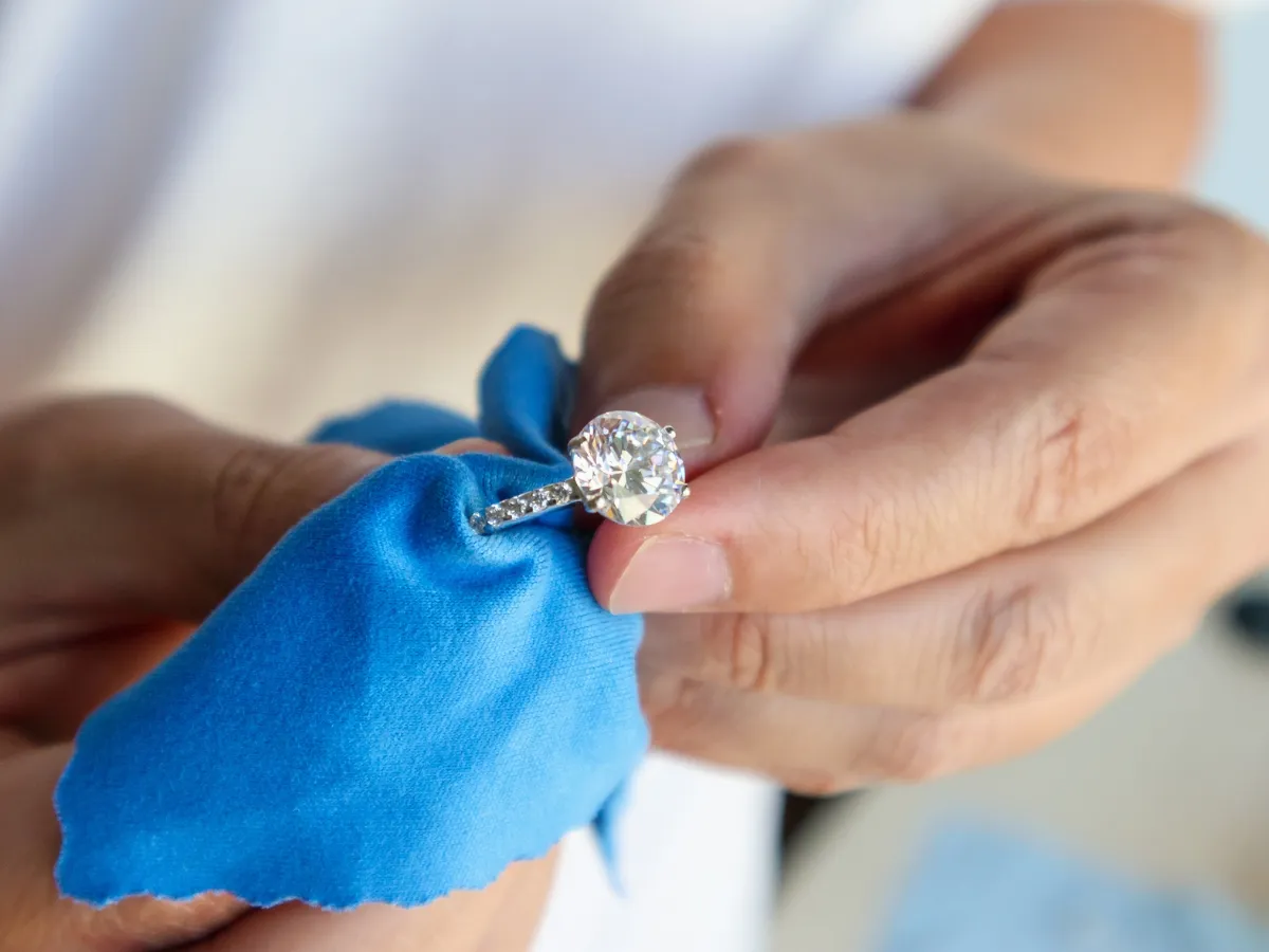 Cleaning engagement ring with blue cloth.