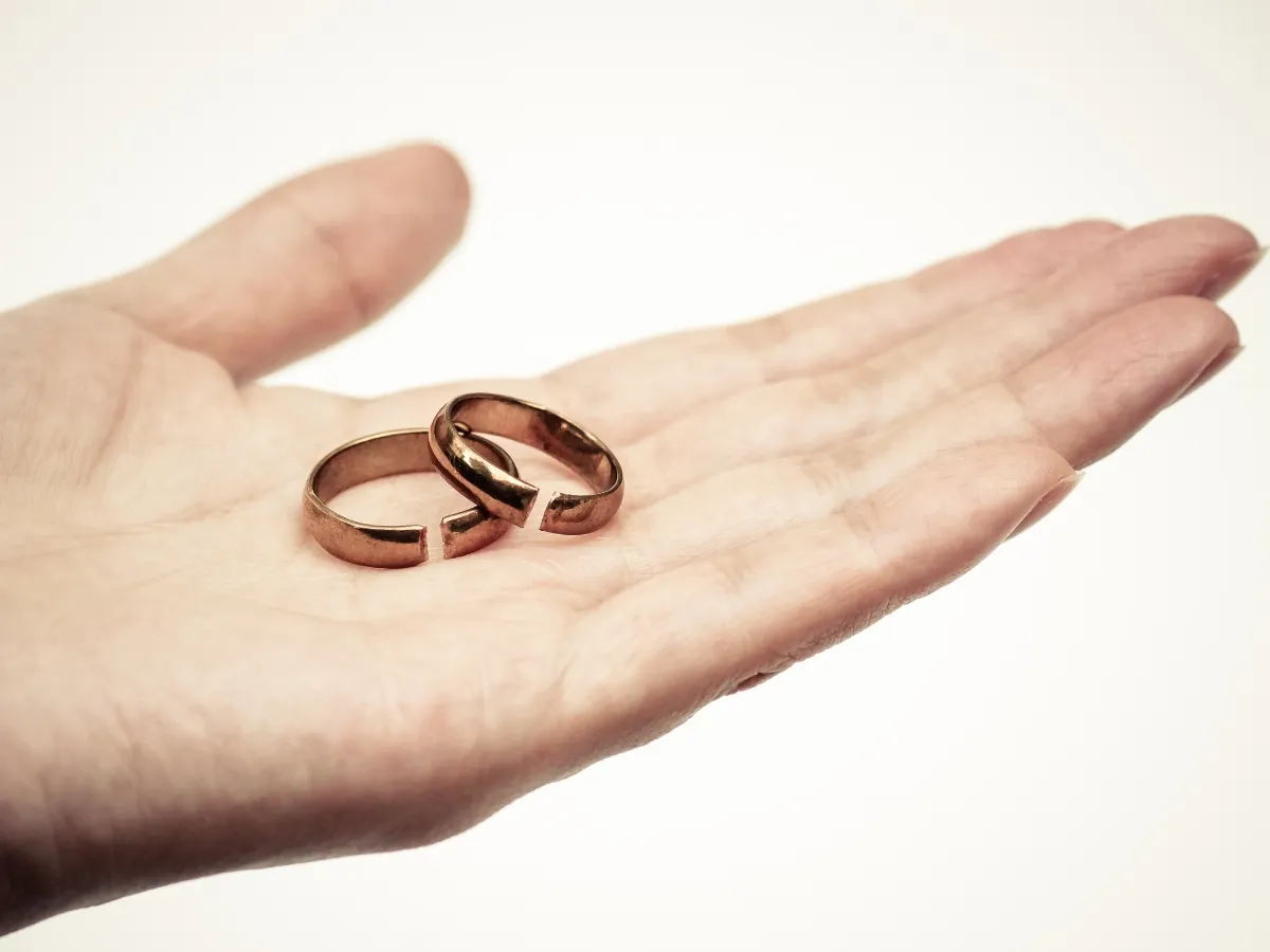 Hand holding two broken rings.