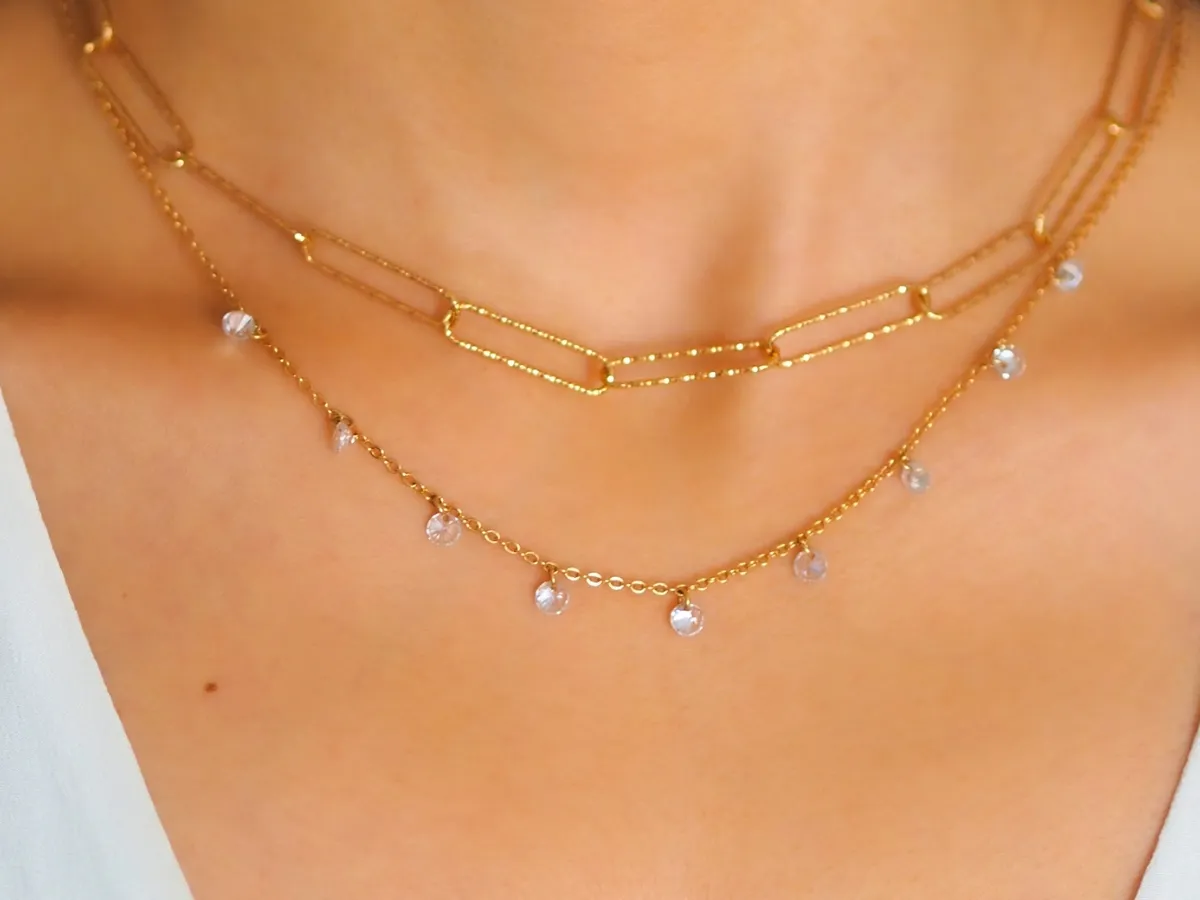 Layered gold necklaces with crystal charms.