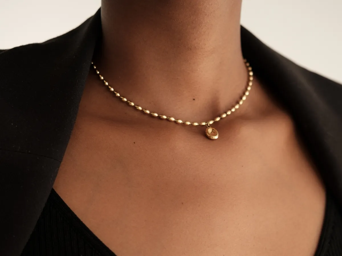 Gold beaded choker with small pendant.