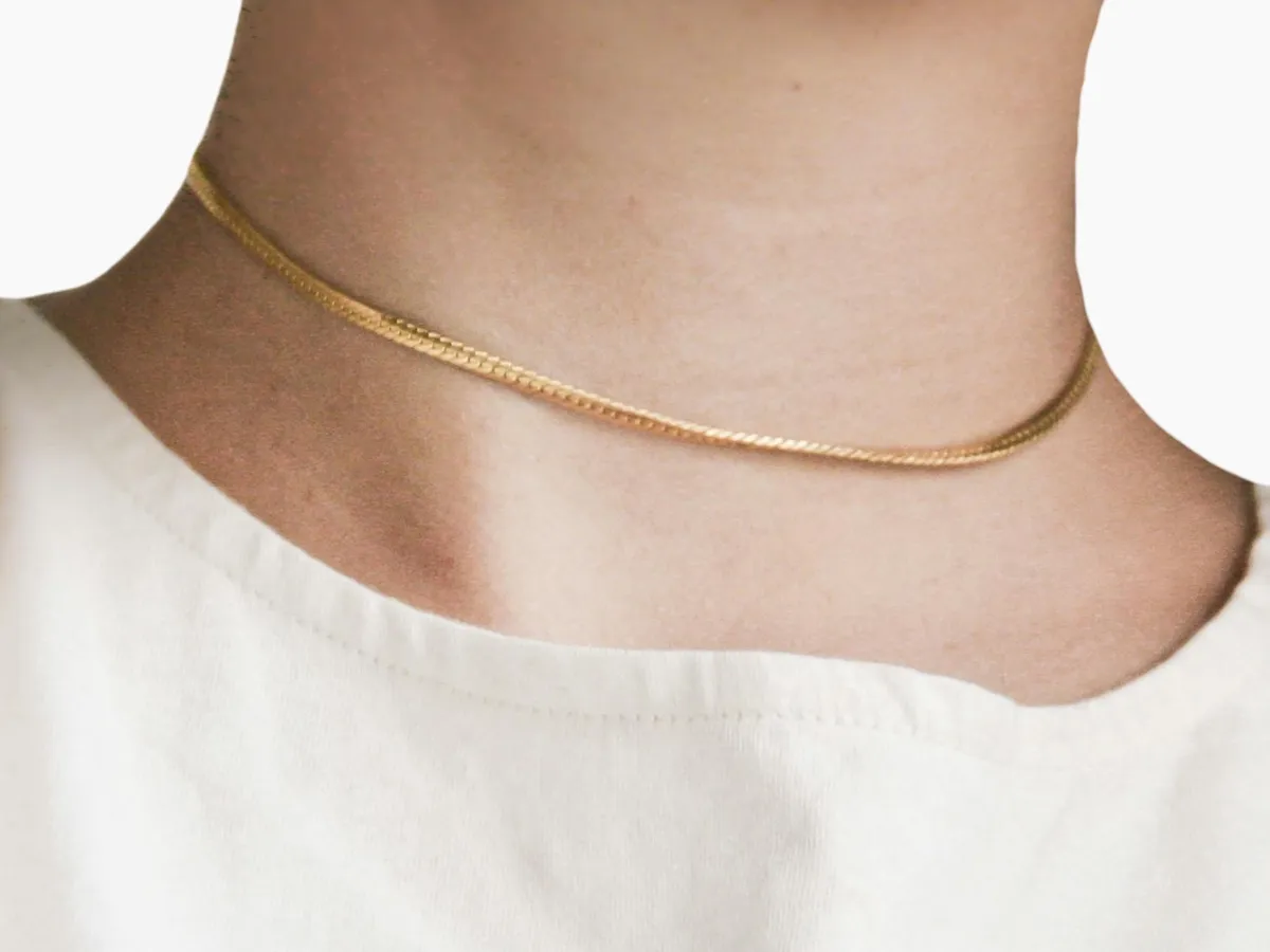 Thin gold herringbone choker necklace.
