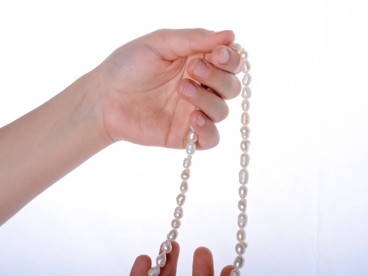 Hand holding freshwater pearl necklace.