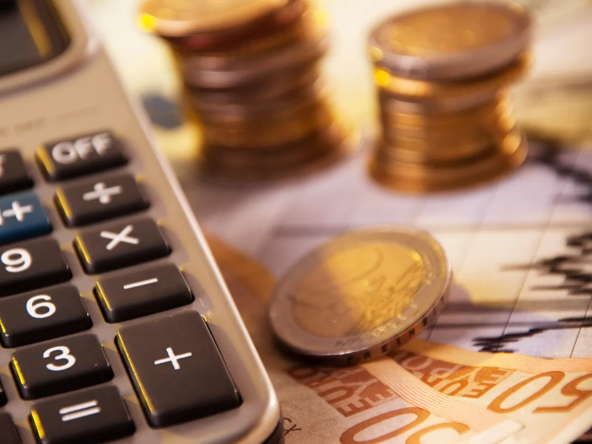 Calculator, coins, and euro banknotes close-up.
